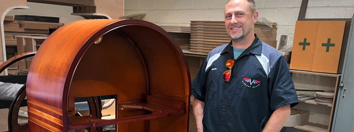 Aaron Schmidt at the Sound Leisure factory next to a new Wurlitzer 1015 cabinet. Picture for jukebox blog.