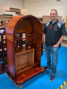 Aaron Schmidt standing next to a new Wurlitzer 1015 cabinet at the Sound Leisure factory.