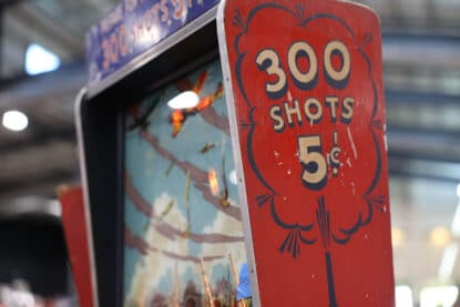 Close-up of a vintage carnival shooting game advertising 300 shots for 5 cents.