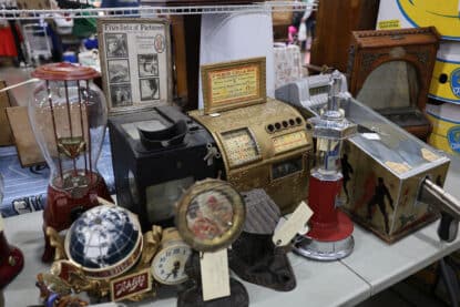 Collection of vintage countertop arcade and vending machines, including peanut dispensers, cigar slot machines, picture viewers, and shooting games.