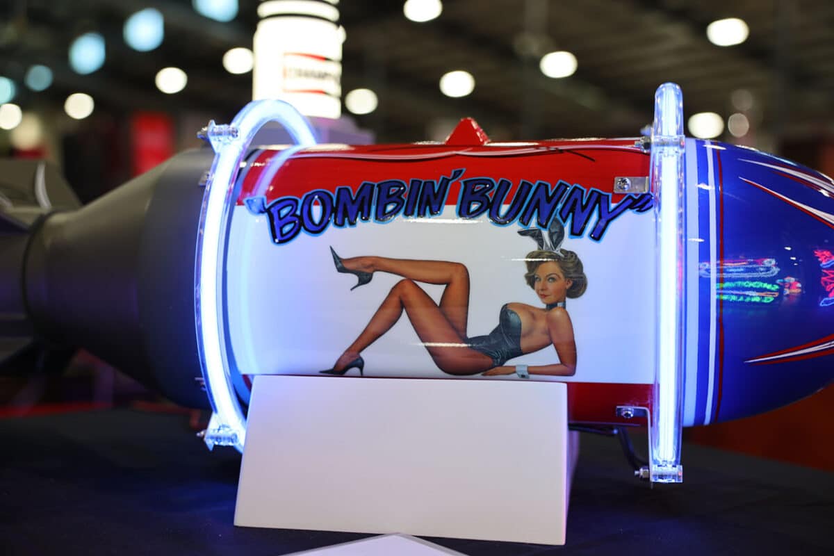 Bomb-shaped neon sign featuring WWII-style pinup art of a woman in bunny ears with the text 'Bombin’ Bunny' on a glossy, patriotic-themed background.