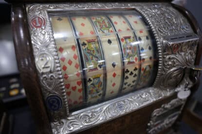 Detailed view of playing card reels on an ornate antique slot machine.