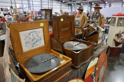 Antique Criterion and Reginaphone disc music boxes with metal tune discs, alongside early phonographs and coin-operated figures at the Chicagoland Coin-Op Show.