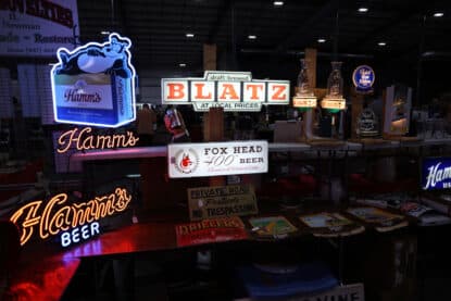Vintage illuminated beer signs for Hamm’s, Blatz, and Fox Head “400” Beer, alongside retro brewery tap handles and signage, on display at the Chicagoland Coin-Op Show.