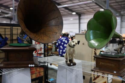 Antique phonograph display featuring a large Victor-style wooden horn gramophone, a green metal Zon-O-Phone, and a “His Master’s Voice” dog statue at the Chicagoland Coin-Op Show.