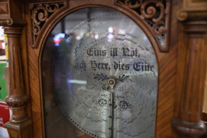 Close-up of a vintage Loetzsch disc music box from Leipzig, Germany, featuring an ornate punched metal music disc with German script and decorative wood cabinet.