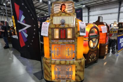 1940-41 Rock-Ola Super Mystic Music jukebox on display at Victory Jukebox booth, surrounded by other illuminated vintage jukeboxes.