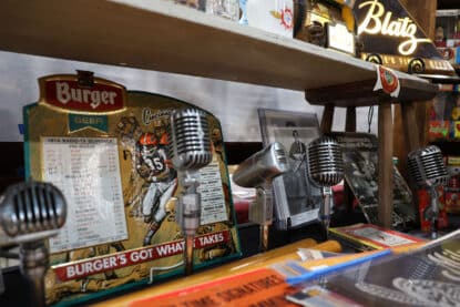 Vintage microphones alongside a Burger Beer Cincinnati Bengals football sign, old records, and a Blatz beer sign at the Chicagoland Coin-Op Show.