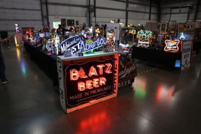 Display of vintage neon beer signs including Blatz, Budweiser, and Miller High Life at an antique show.