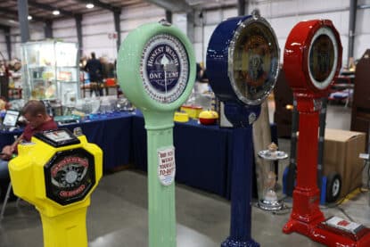 Row of brightly colored vintage penny scales, each restored in vibrant paint schemes, with slogans like "Honest Weight One Cent" and "Did You Weigh Yourself Today?" displayed.