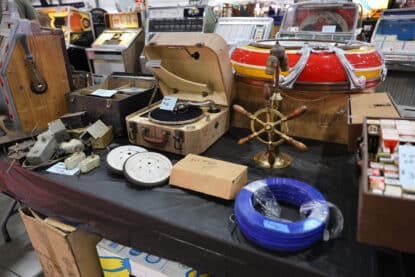 Vintage phonograph, jukebox dome, and assorted antique audio parts displayed on a vendor table at a collector fair.