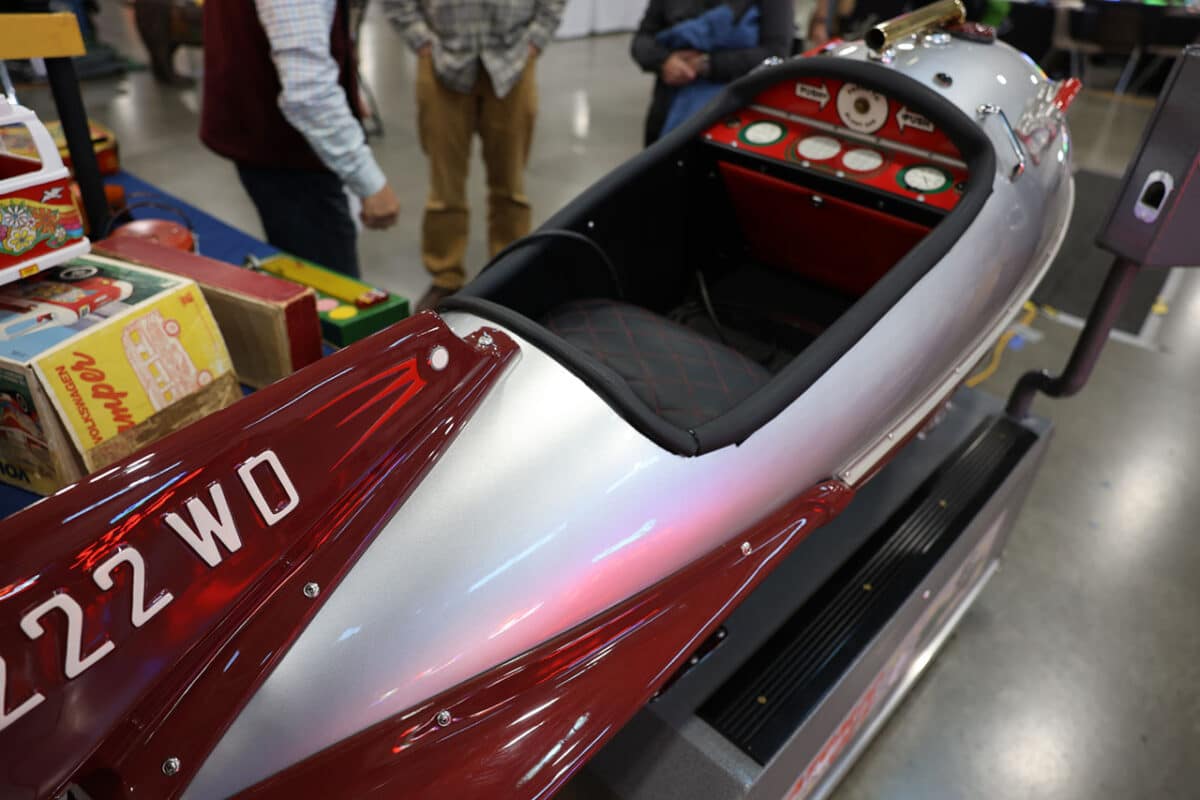 Restored coin-operated rocket kiddie ride with red and silver finish, detailed dashboard, and quilted seat.
