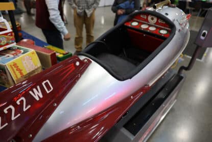Restored coin-operated rocket kiddie ride with red and silver finish, detailed dashboard, and quilted seat.