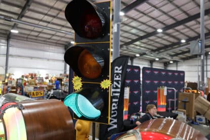 Restored traffic light with illuminated green signal next to Wurlitzer booth at antique exhibition.