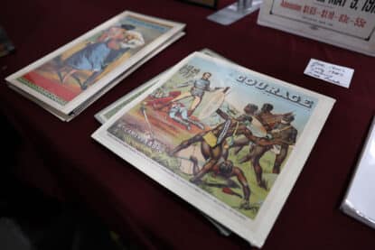 Antique lithograph print titled “Courage” by Wm. Cameron & Bro., depicting a battle scene with African warriors and colonial soldiers, displayed at the Chicagoland Coin-Op Show.