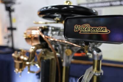 Close-up of a vintage Waterman Porto Motor outboard engine with polished brass and copper details.