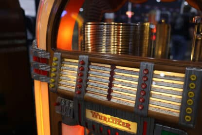 Close-up of a restored Wurlitzer 1015 jukebox with illuminated sides, red selection buttons, and visible record carousel.
